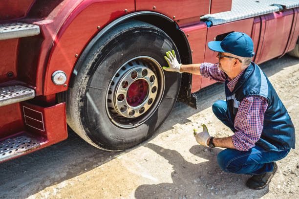 Truck driver inspecting tires and checking depth of tire tread for safe ride. Controlling vehicle before transportation service